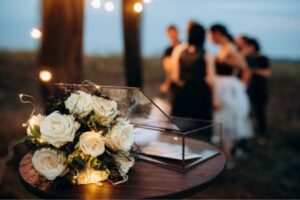 Wedding flowers on table with guests in the background.
